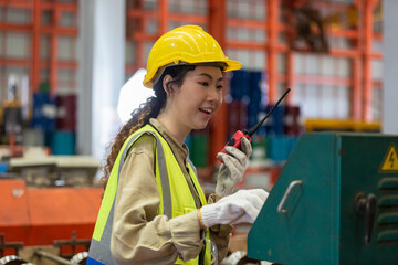 happy smile women engineer holding walkie talkie quality control machine standing at factory warehouse. professional engineering machinery workshop.