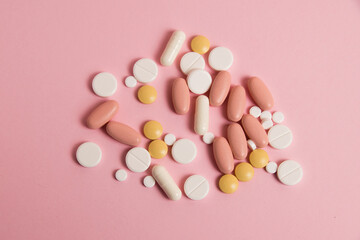 Flatlay, many different pills on a pink background