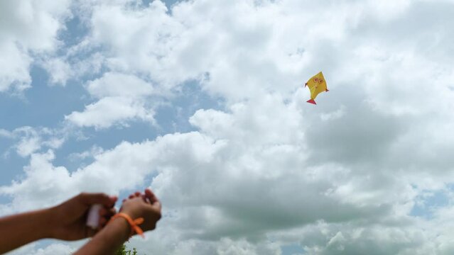 close up shot of hands flying kite in a cloudy sky during Sankranthi festival - concept of freedom, flying higher and imagination.