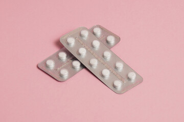 White pills in a blister on a pink paper background. Concept of treatment of diseases and support of the body in spring - obrazy, fototapety, plakaty