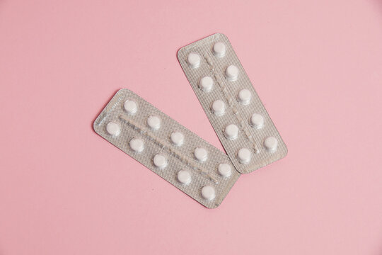 White pills in a blister on a pink paper background. Concept of treatment of diseases and support of the body in spring