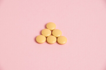 Yellow vitamins in pills on a pink paper background. Concept of immunity support in spring.