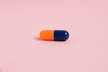 Multicolored pill on pink paper background with copy space, macro. Concept of treatment of covid 19 and colds.