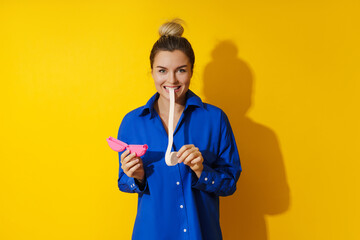 Young woman tasting chewing gum against yellow background