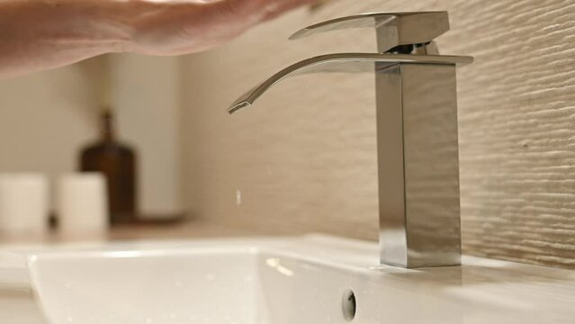 Girl hand and water faucet in bathroom