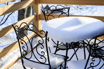 Fototapeta na wymiar Outdoor table and chairs covered in snow after the first snowfall
