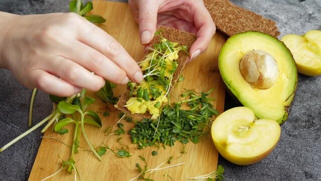 Veganuary. The girl prepares breakfast from avocado and green shoots. Eco healthy food. The use of micro greens in food. meat free diets