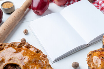 blank opened cooking book mockup with apple pie, meat pie and seasonal fruit