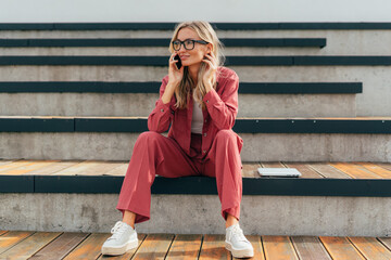 Young business woman talking on a mobile phone outside.