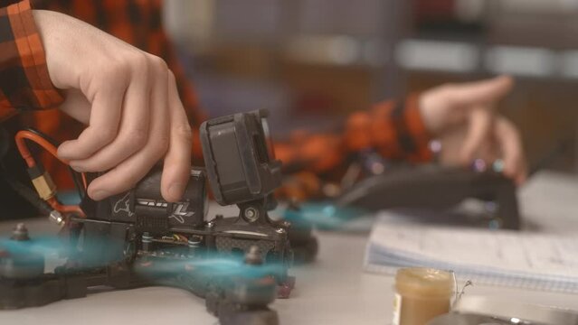 Worker solders device chip repairing broken item at table in studio closeup. Master assembles gadget at workplace