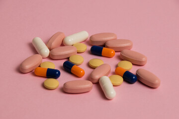 Colorful pills and medical capsules macro on pink background, side view