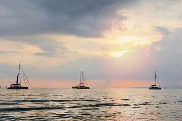 Sea with silhouettes of various boats against a sunset sky