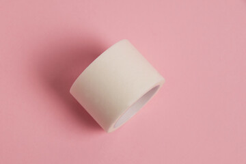 White medical patch on a paper base, for applying bandages, on a pink background