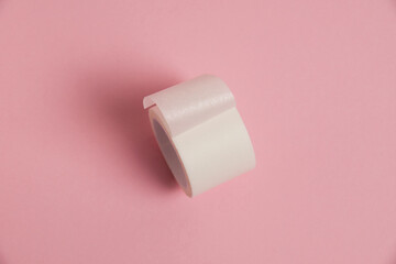 White medical patch on a paper base, for applying bandages, on a pink background