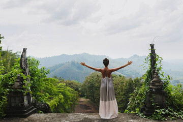 Woman standing amidst the ruins of an ancient Asian palace, wearing a long beautiful dress