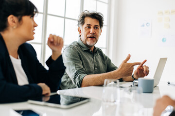 Senior man talking to his team during a meeting in an office