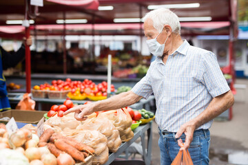 mature european man wearing medical mask protecting against the virus buying potatoes in market
