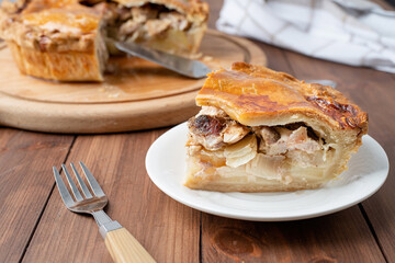 Homemade meat pie with greenery on wooden background