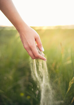 Sand slipping through a young woman's hands in a dreamy coastal environment