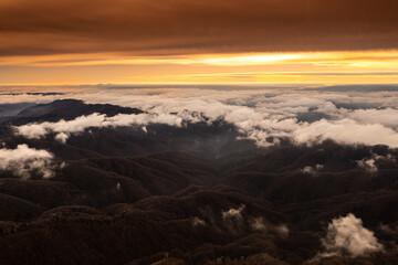 Sea of clouds over the mountains. Amazing sunset landscape over the foggy hills during an autumn day. Nature and travel aerial photos.