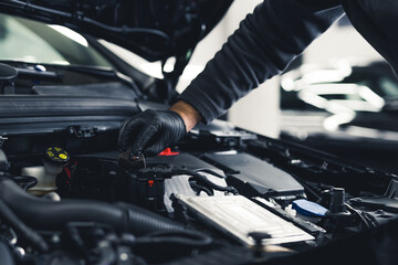 Close-up shot of unrecognisable man wearing black glove inspecting car engine and interior of hood...