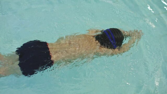 kids swimming class training pool. male child learning make butterfly hands movements in water pool. swimming workout 5 years old boy kid. little swimmer training class. young sportsman swims in pool