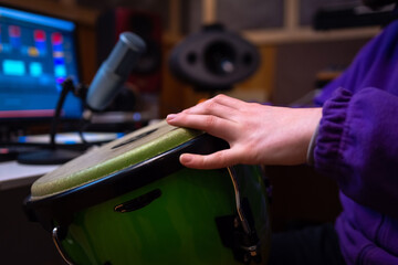 Man plays the drum in a recording studio. Records the sound of a drum using a microphone and a computer