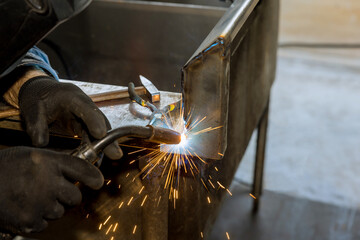 An argon gas shielded arc welding machine is used by worker to weld metal with sparkle on semi...