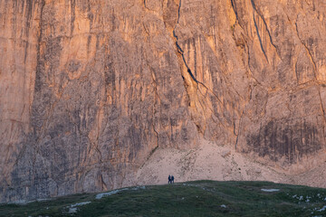 Two hikers silhouette and a dolomite mountain illuminated at sunset