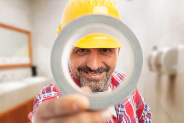 Close-up on smiling man worker holding duct-tape over his face