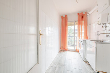 Modest and old kitchen with little furniture with access to a terrace with orange curtains