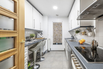 kitchen with white furniture on both sides of the room with gray countertops and matching profiles,...