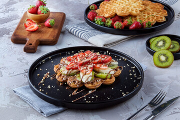 Homemade waffles with berries in plate on grey wooden table