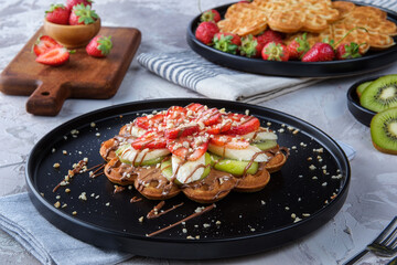 Homemade waffles with berries in plate on grey wooden table