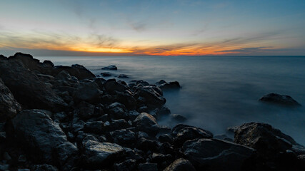 Fototapeta na wymiar Wide angle long exposure shot of sunset at sea. Coastal rocks in the foreground. Black sea shore.