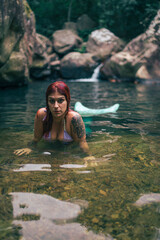 Sirena pelirroja en una gruta rio con agua encantado manantial misterioso en bosque frondoso y verde