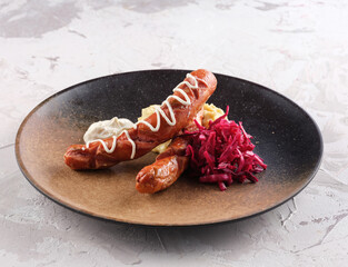 Grilled sausage with herbs and vegetables added to the grill plate outdoors. grilled food, barbecue