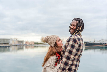 a multiracial couple standing on the pier laughing