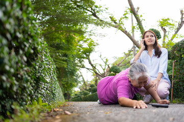Naklejka na ściany i meble Asian senior woman fell down on lying floor because faint and limb weakness and pain from accident and woman came to help support and call emergency. Concept of old elderly insurance and health care