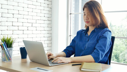 Fototapeta na wymiar Asian Female freelance using laptop at home office desk. Woman reading financial graph chart Planning analyzing marketing data. Asian female people working office firm with business stuff, coffee cup