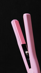 Planchas de pelo de color rosa sobre fondo negro con copyspace
