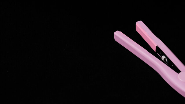 Planchas de pelo de color rosa sobre fondo negro con copyspace