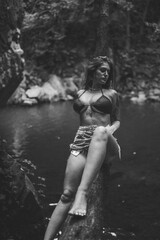 Chica guapa morena española en bikini en un rio de un bosque verde frondoso y natural