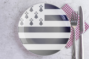 A Plate with the Flag of Brittany, Cutlery and Napkins on the Mable Table.