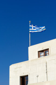 Greek flag on the building in a blue summer sky. Vertical image.