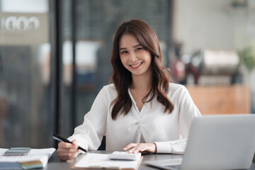Fototapeta premium Happy smiling Asian businesswoman working and looking at the camera in office room.