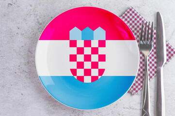 A Plate with the Flag of Croatia, Cutlery and Napkins on the Mable Table.