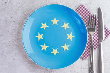 A Plate with the Flag of European Union, Cutlery and Napkins on the Mable Table.