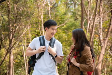 Happy love couple take photo and selfie during camping and relax in forest hiking trip, beautiful Asian woman and handsome man happiness spend time tpgether, sunset liesure romantic moment