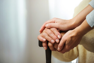 Helping hand for the elderly concept with young hand holding old hand. Senior woman with aged...